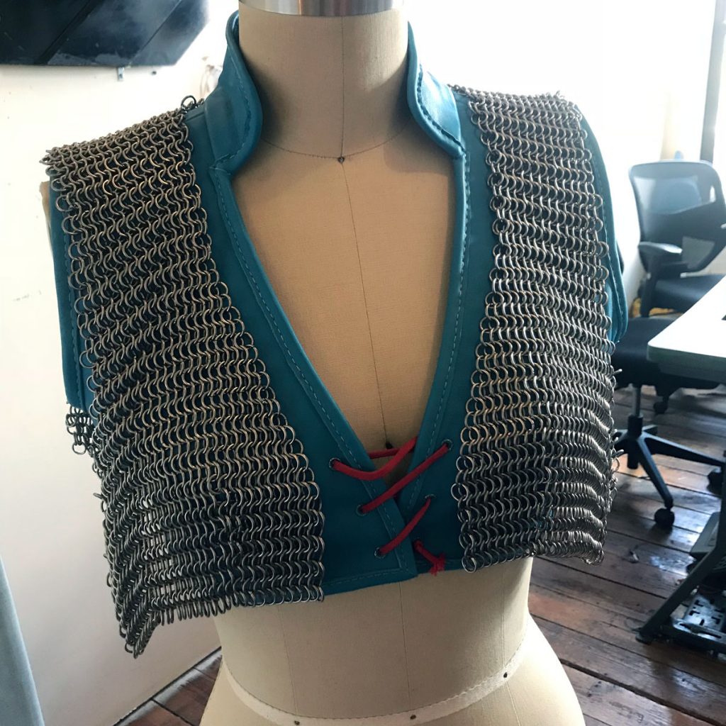 Chainmail vest loosely draped over leather vest on dress form