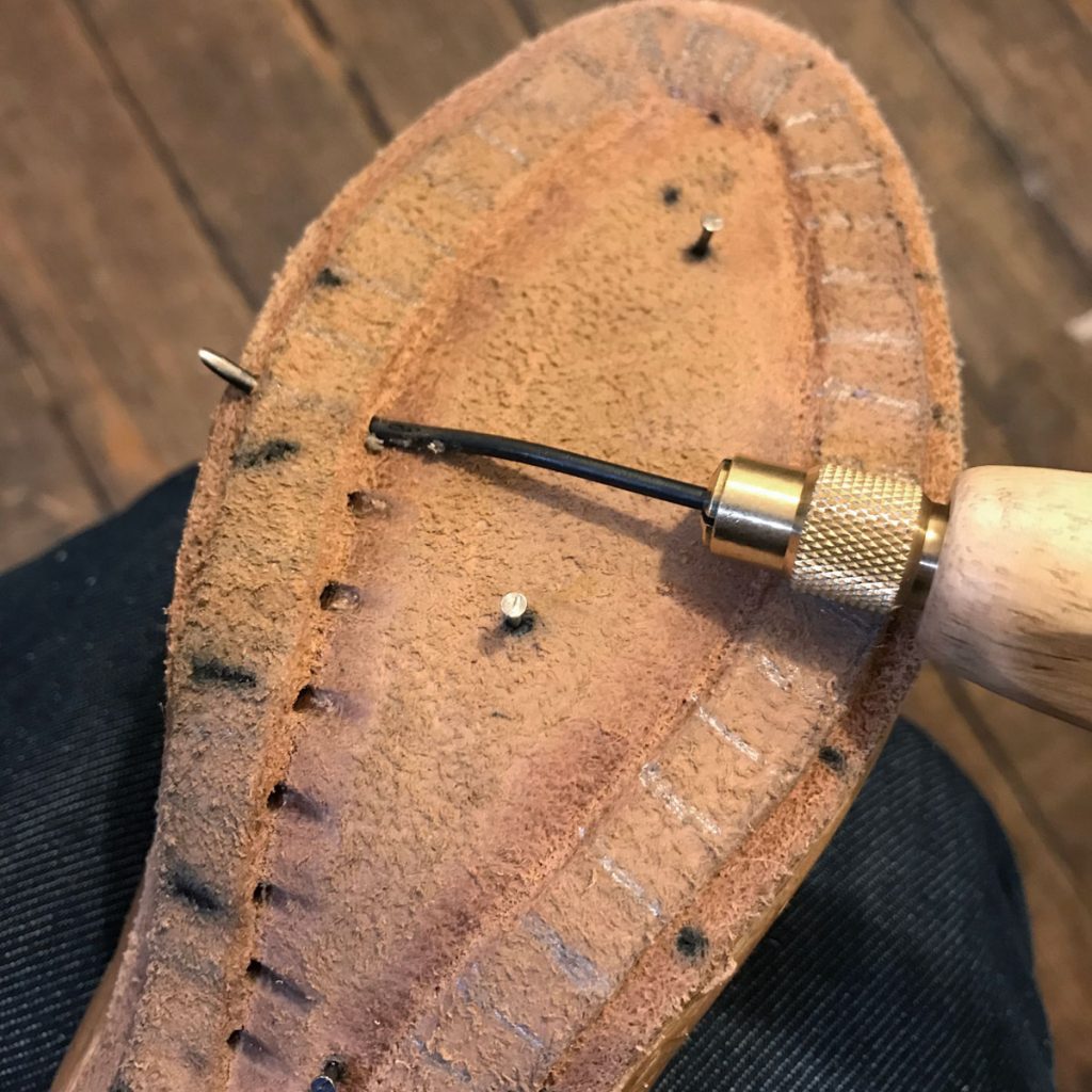 using a curved awl to poke holes for stitching